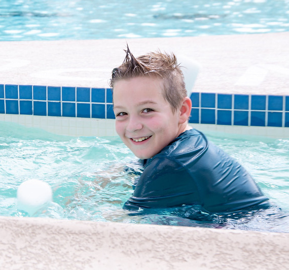 kid in pool with pool noodle learning to swim