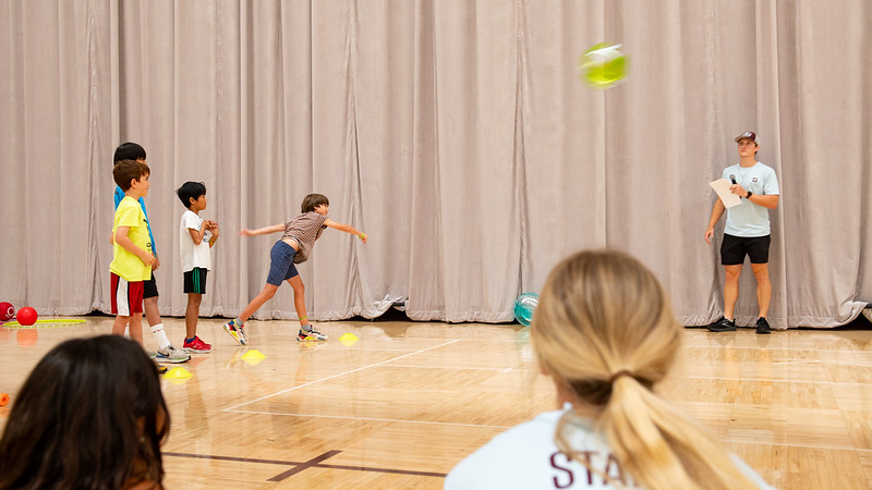 Kids throwing a beach ball across the room. Counselors are watching.