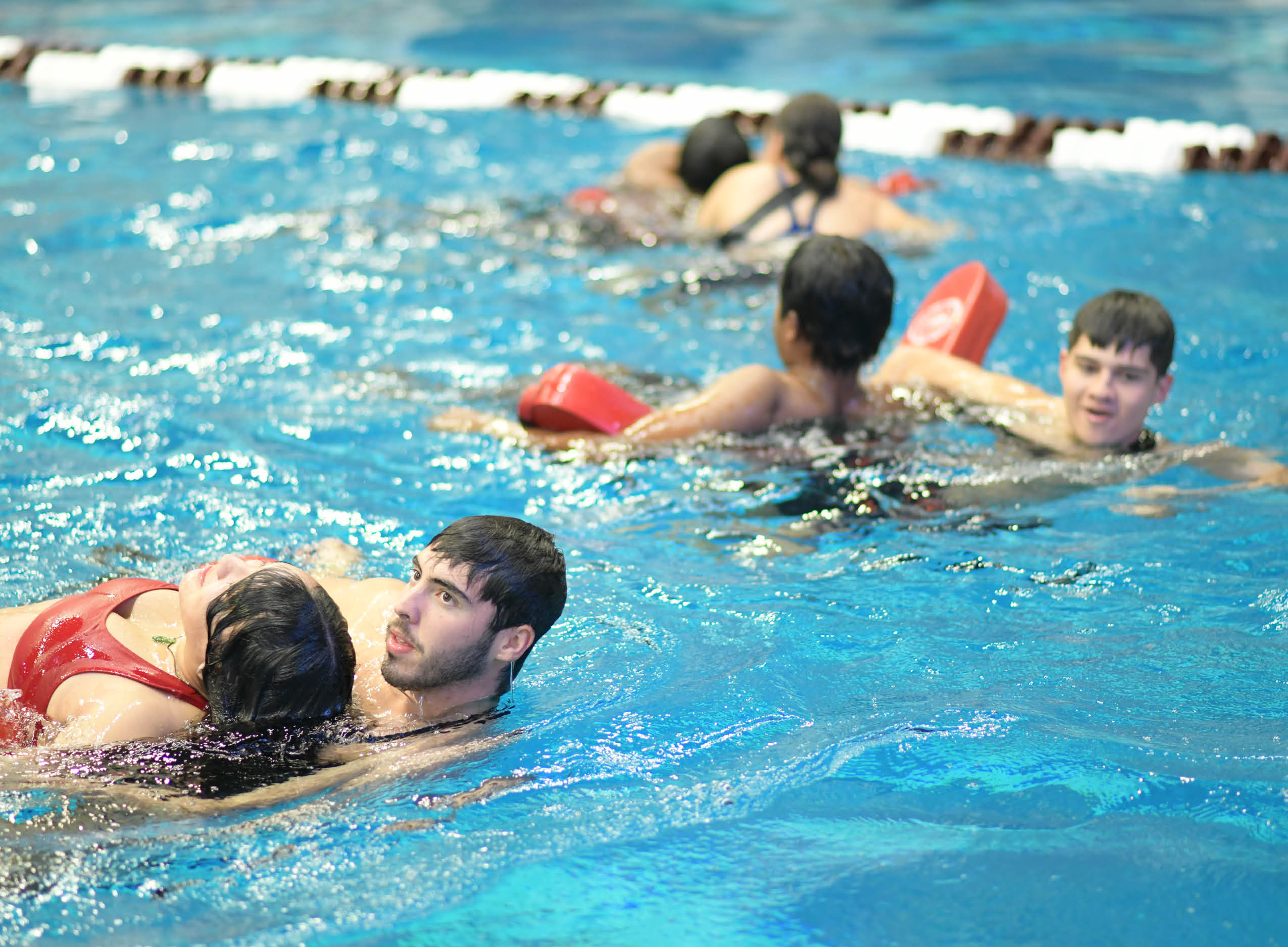 Lifeguards practicing saving procedures in the pool using the lifeguard rescue tube.