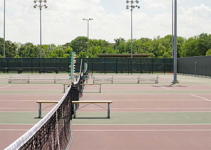 A tennis court with a net and benches.