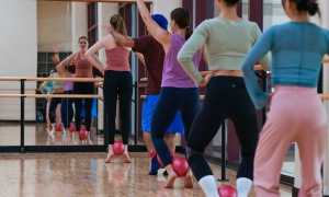 Five women doing barre ballet exercises