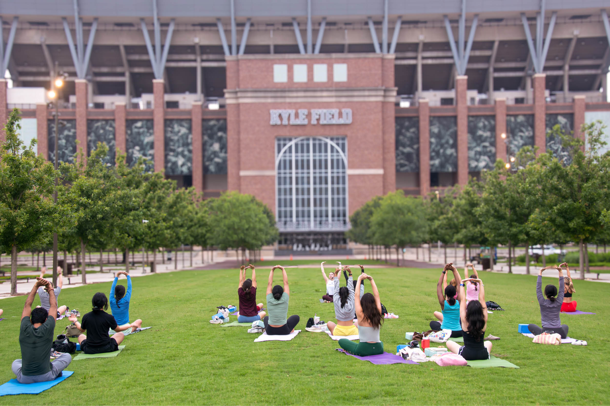 Students participate in a group fitness class on the grass in front of Kyle Field at Texas A&M.