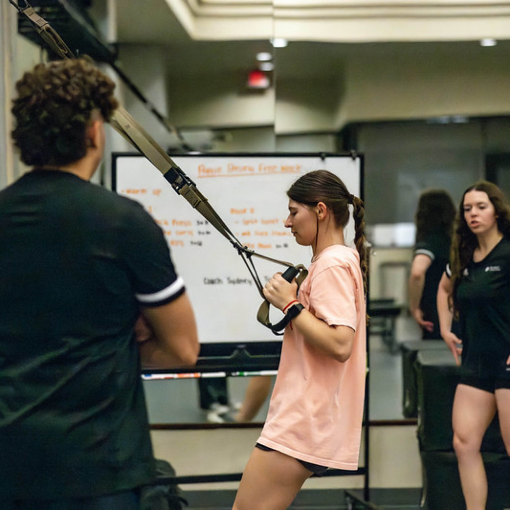 F25_Rec Free Week_WR_Intro to training Female training on the roes in the PT suite with two trainers instructing her