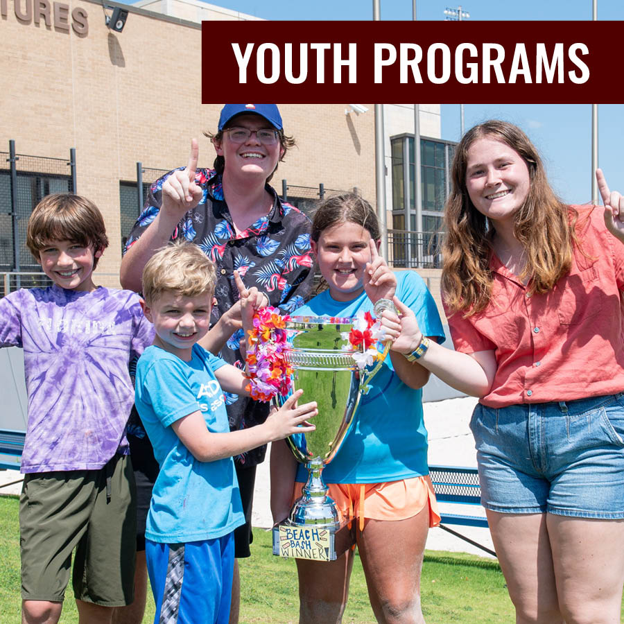 Children and staff smiling and holding a large trophy labeled “Beach Bash Winner” with the title “Youth Programs.”