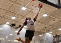 Student in a Texas A&M jersey leaping to make a basketball layup in the Student Rec Center gymnasium.