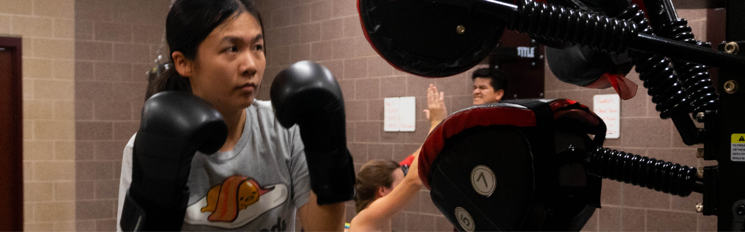 A women wearing boxing gloves and is ready to make a punch in a boxing bootcamp.