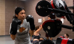 A women wearing boxing gloves and is ready to make a punch in a boxing bootcamp.