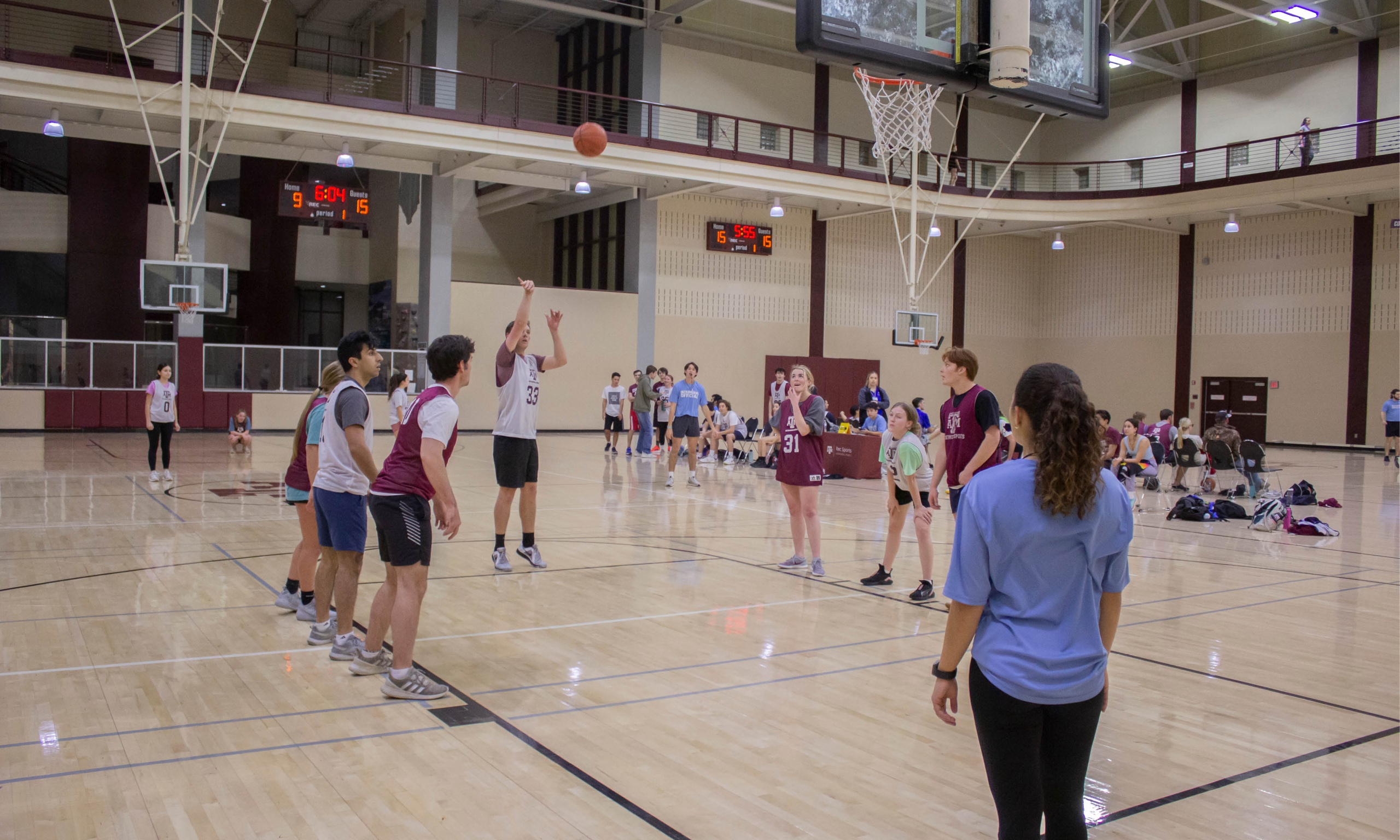 A dynamic atmosphere fills the gymnasium as a group of individuals actively engage in a game of basketball, demonstrating their agility, coordination, and love for the sport.
