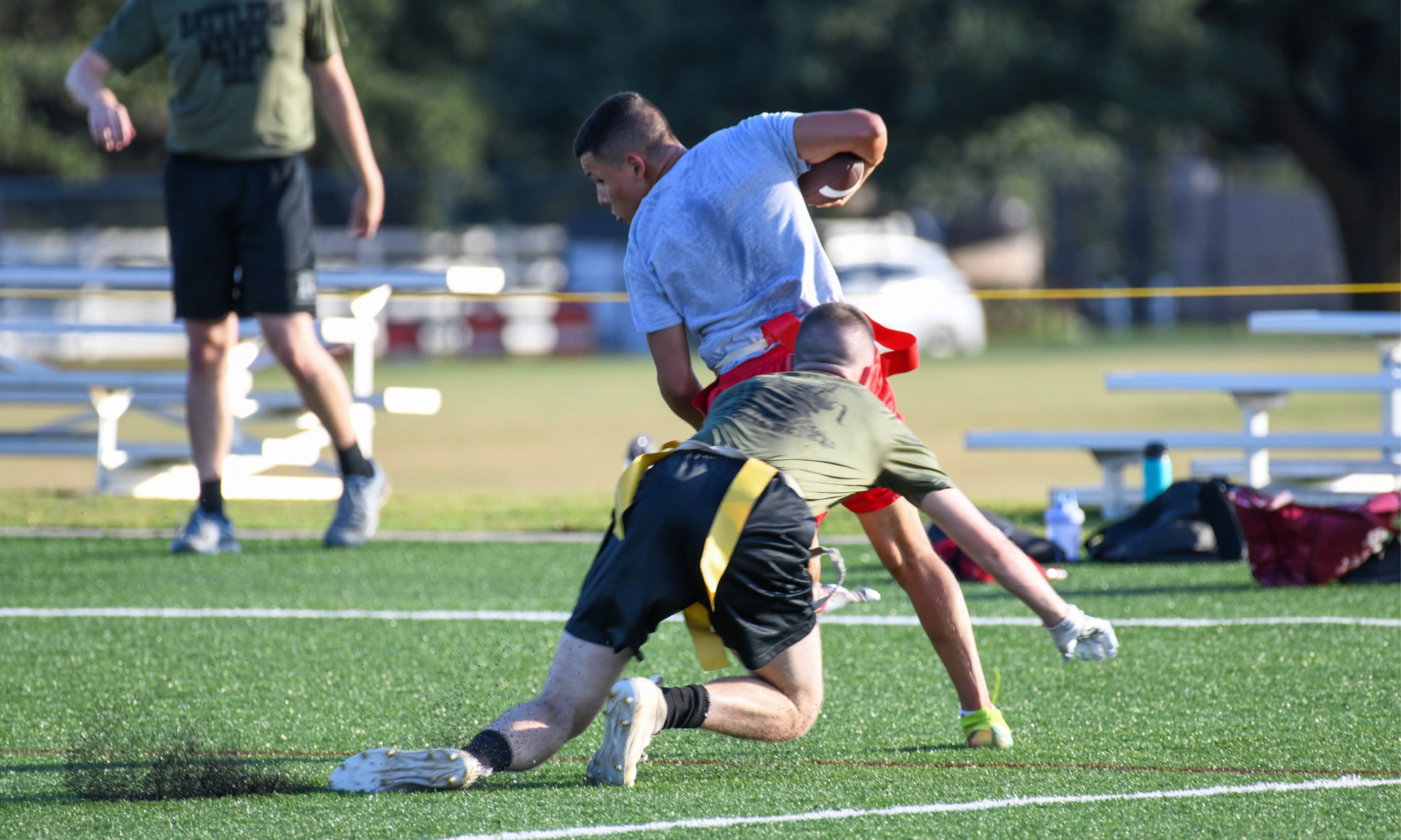 Player making a grab for a football in game of flag football.