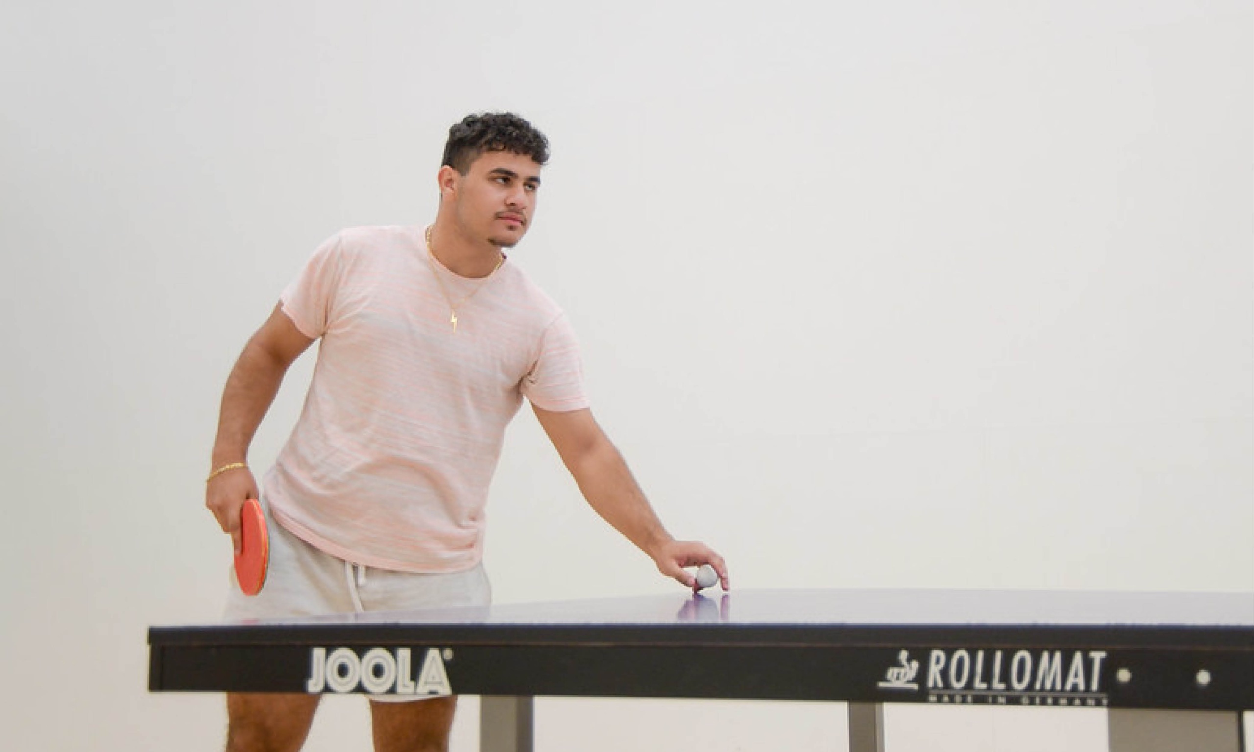 Man standing at a ping pong table in one of the racquetball courts at the Student Rec Center