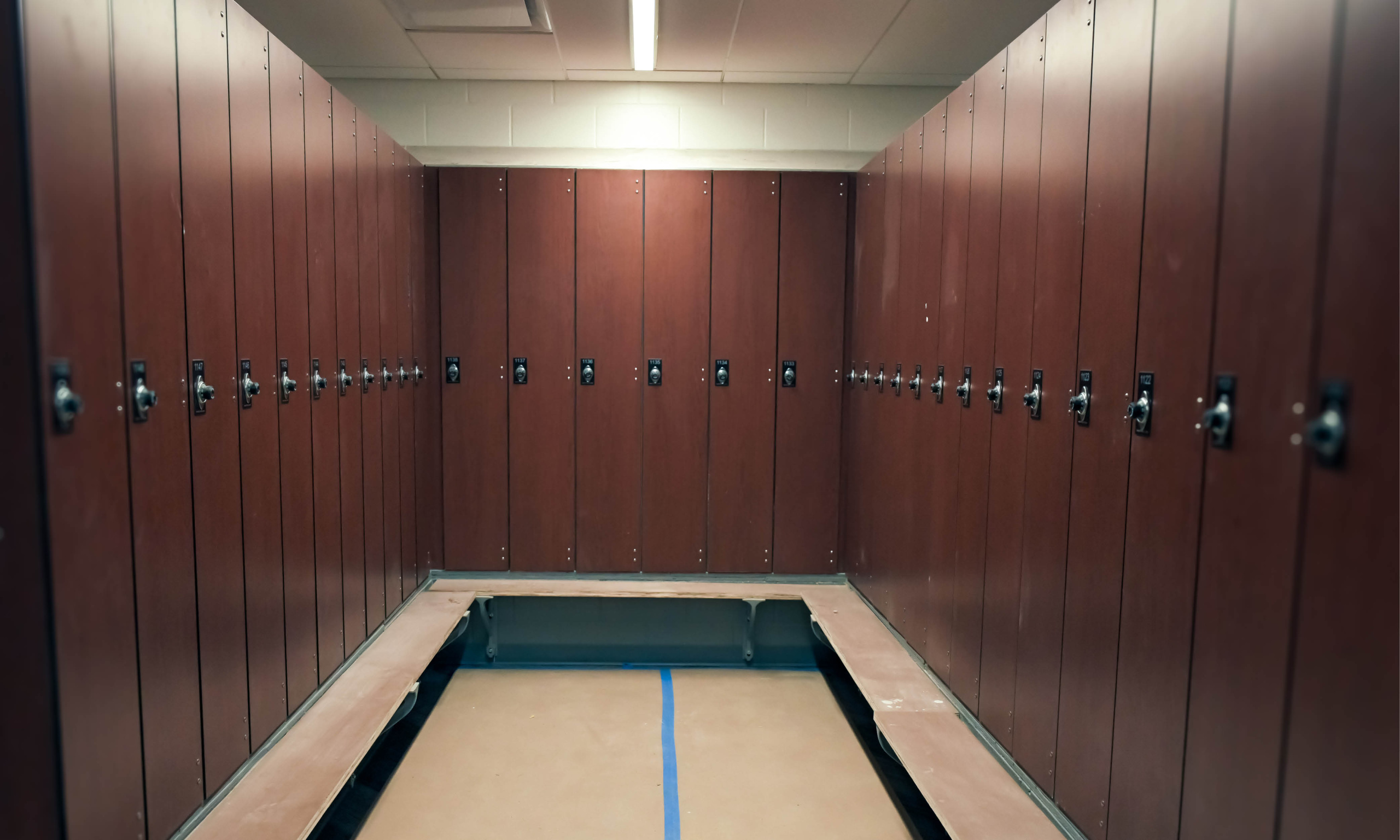 Renovated locker room with rows of tall wooden lockers and built-in bench seating.