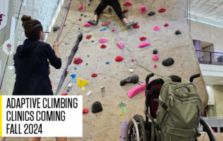 Adaptive climber, sitting in her wheelchair learning to tie in to the climbing rope while at the base of the rock wall with a climbing instructor.. Text written on the bottom of the image states "Adaptive Climbing Coming fall 2024"