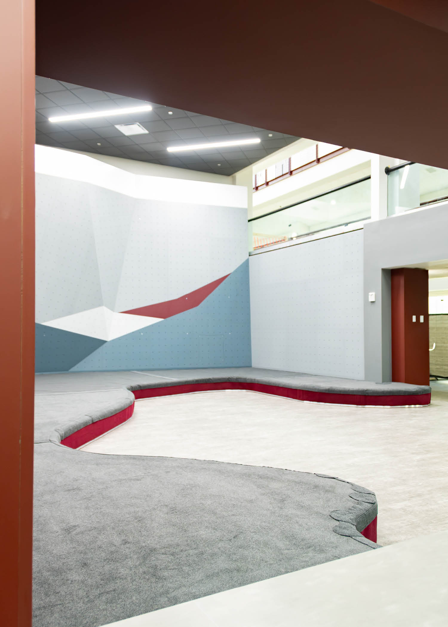 The new Texas A&M Rec Center bouldering wall featuring geometric gray, white, and maroon panels with new Strati padding installed at the base.