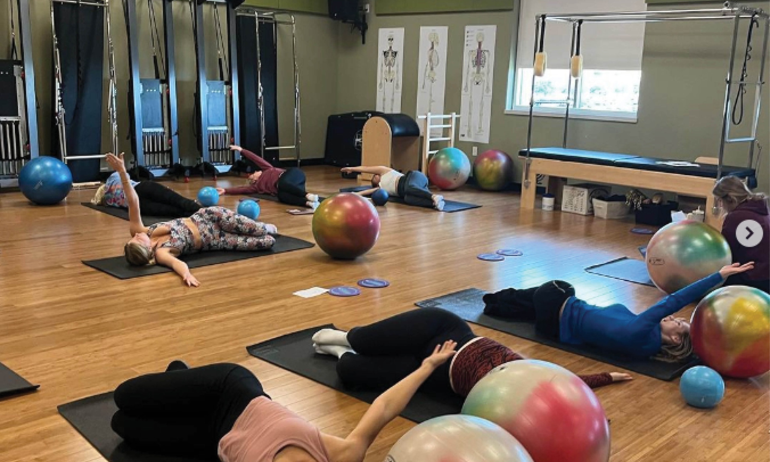 A group of people doing pilates in a room with yoga balls.