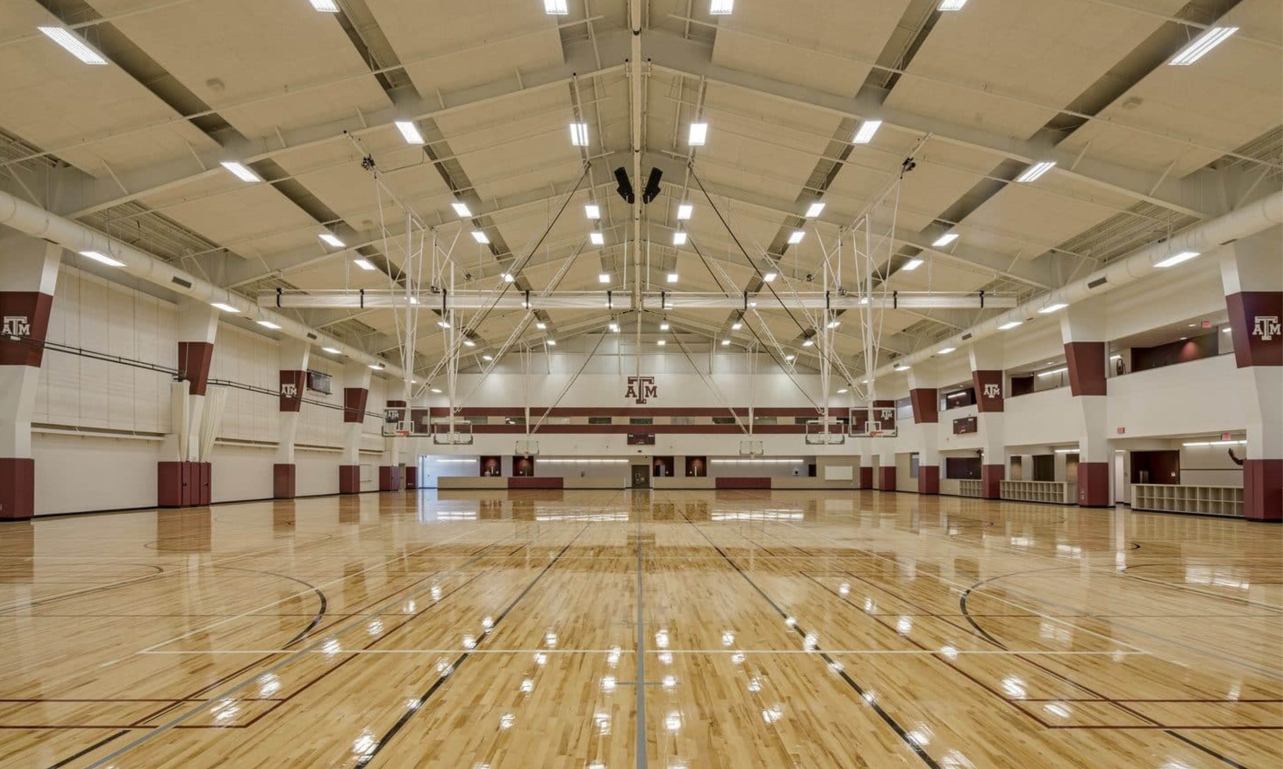 Spacious indoor basketball court with ceiling lights.
