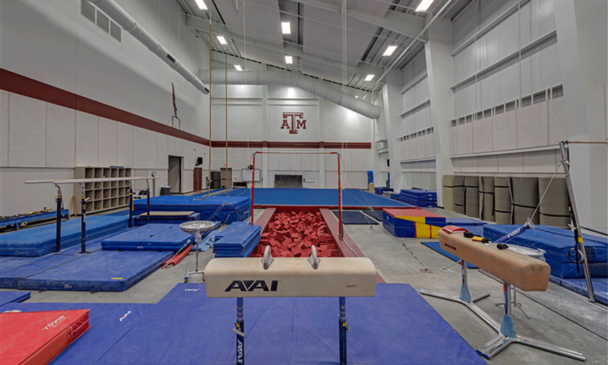 A spacious gymnastics gym filled with mats and equipment, offering ample room for gymnasts to practice and perform their routines.