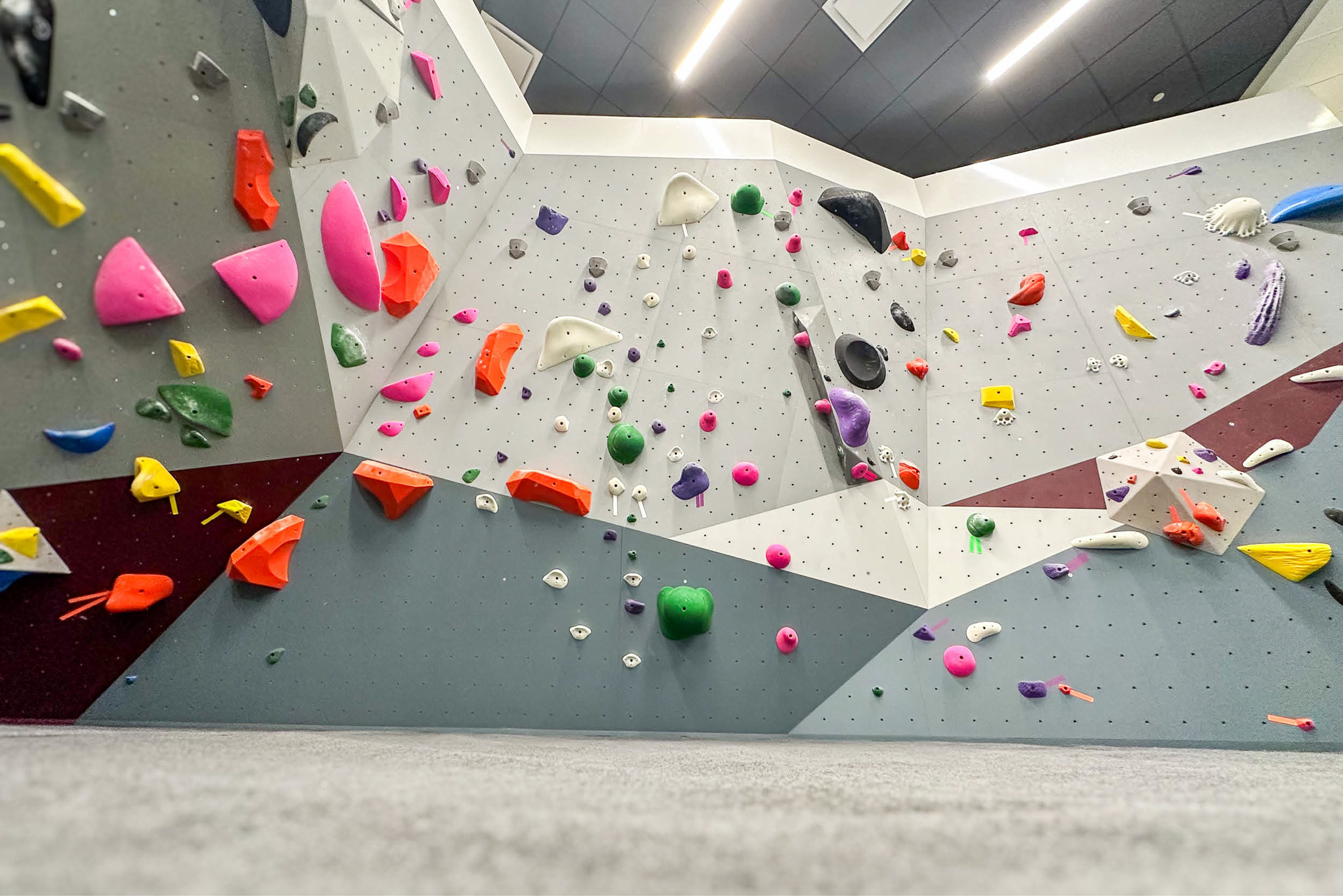 Side view of the new bouldering wall at Texas A&M Rec Sports displaying colorful routes and textured climbing surfaces.