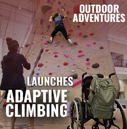 Outdoor Adventures launches adaptive climbing program, featuring an individual climbing an indoor rock wall and another person watching, with climbing gear and a wheelchair visible in the foreground.