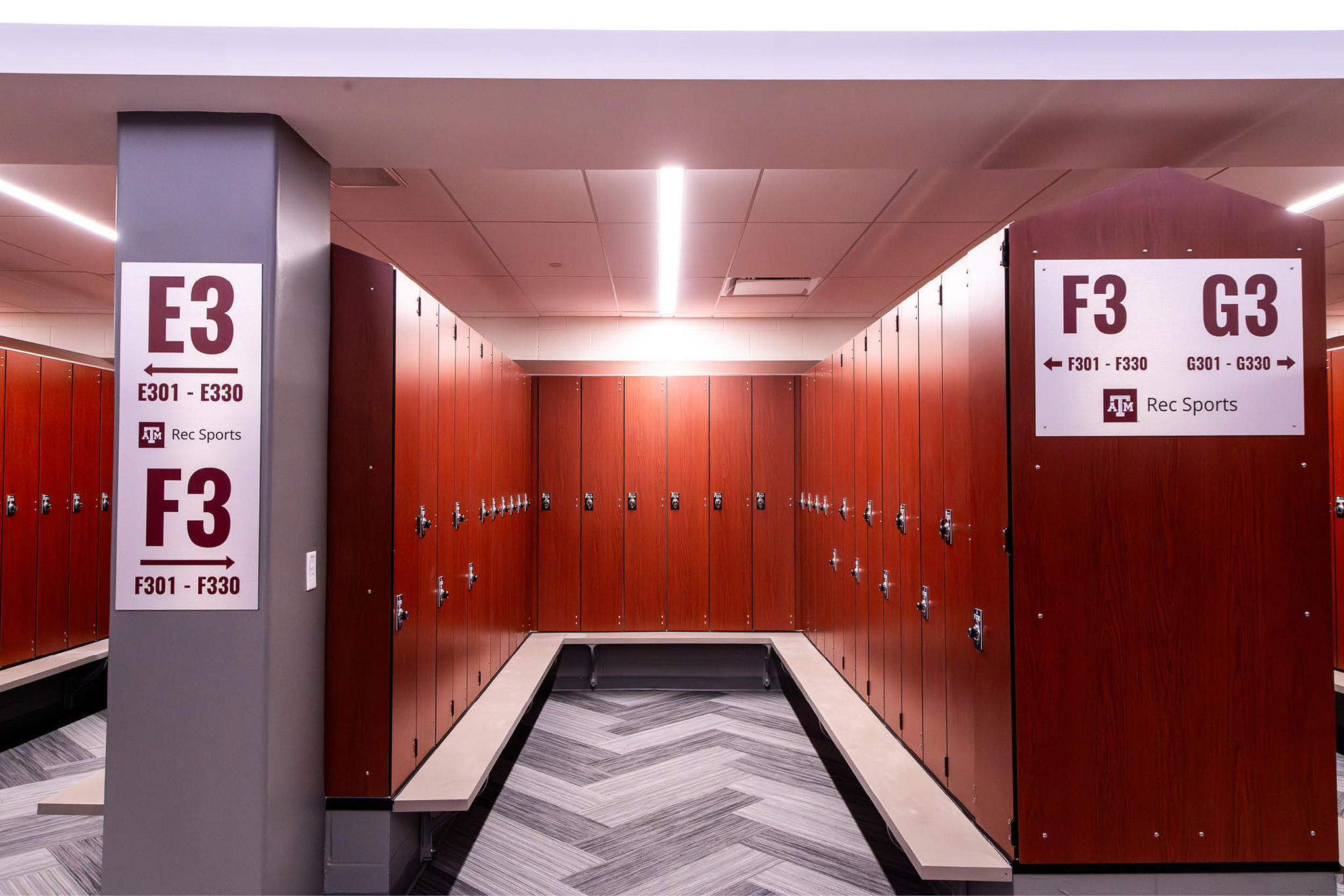 Rows of new wood-finish lockers in the renovated locker rooms at Texas A&M Rec Sports with maroon Rec Sports signage.