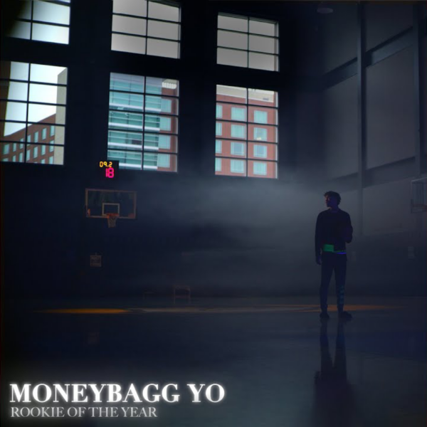 Album cover for 'Rookie of the Year' by Moneybagg Yo, featuring the artist standing alone in a dimly lit basketball gym with a scoreboard in the background.