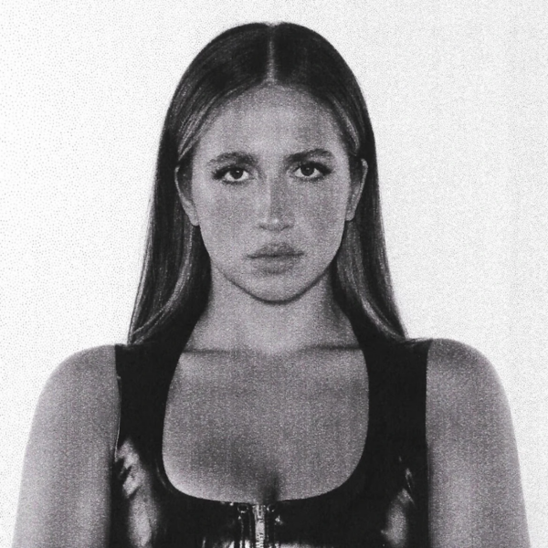 Black and white portrait of a person with long straight hair, wearing a zippered top, and looking directly at the camera.