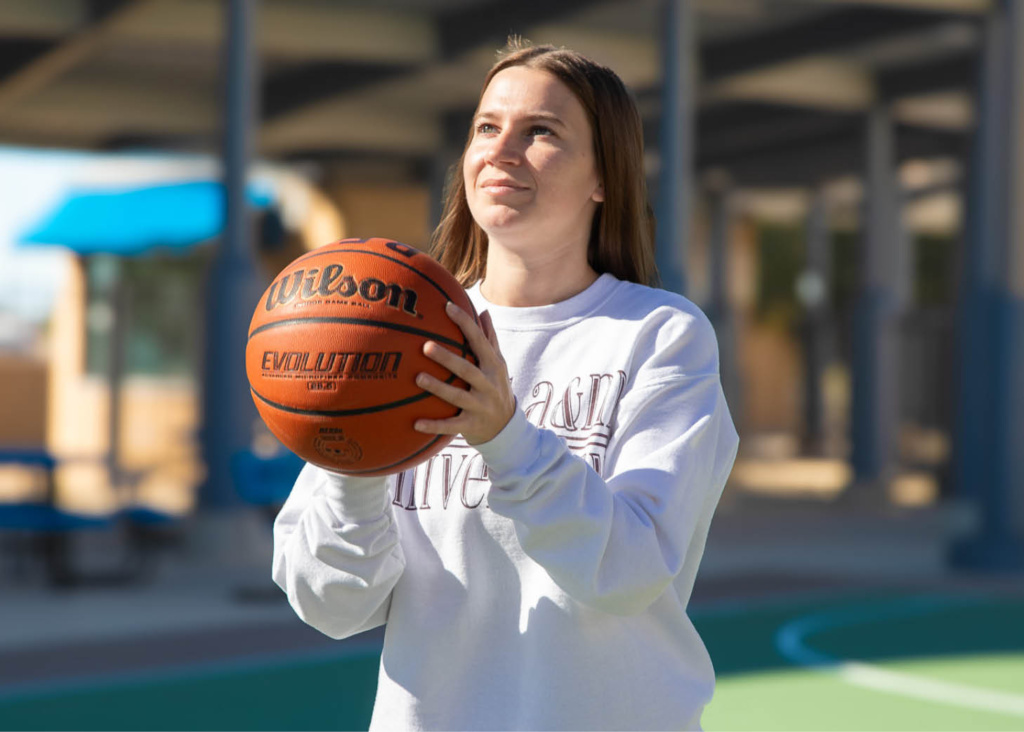 Sports_basketball Person holding a Wilson basketball on an outdoor court.