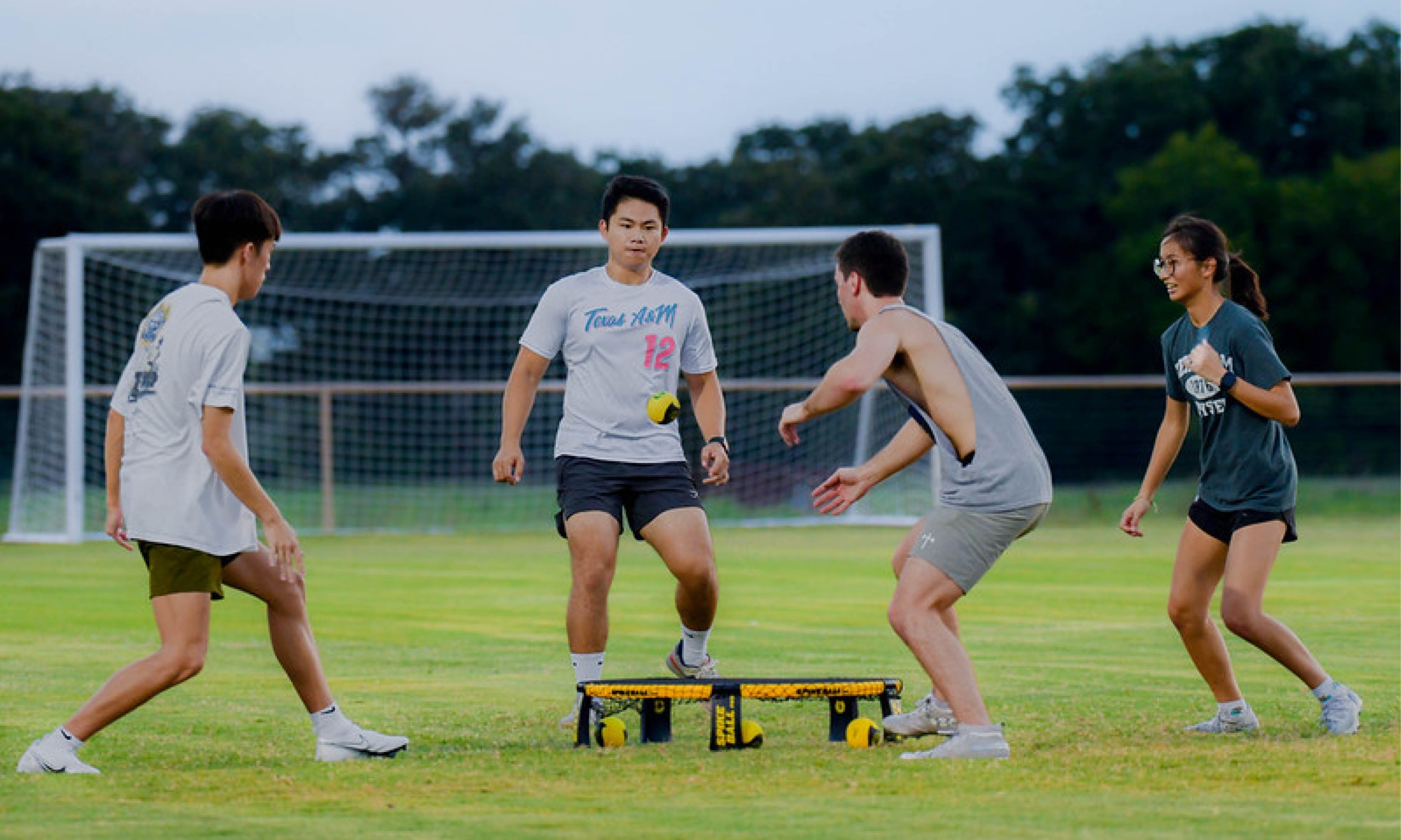 Four young men playing spikeball on a field, displaying teamwork, agility, and passion for the game.