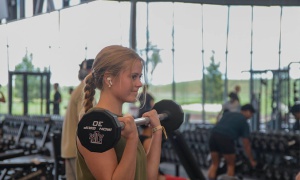 Women in strength & Conditioning room lifting a barbell weight.