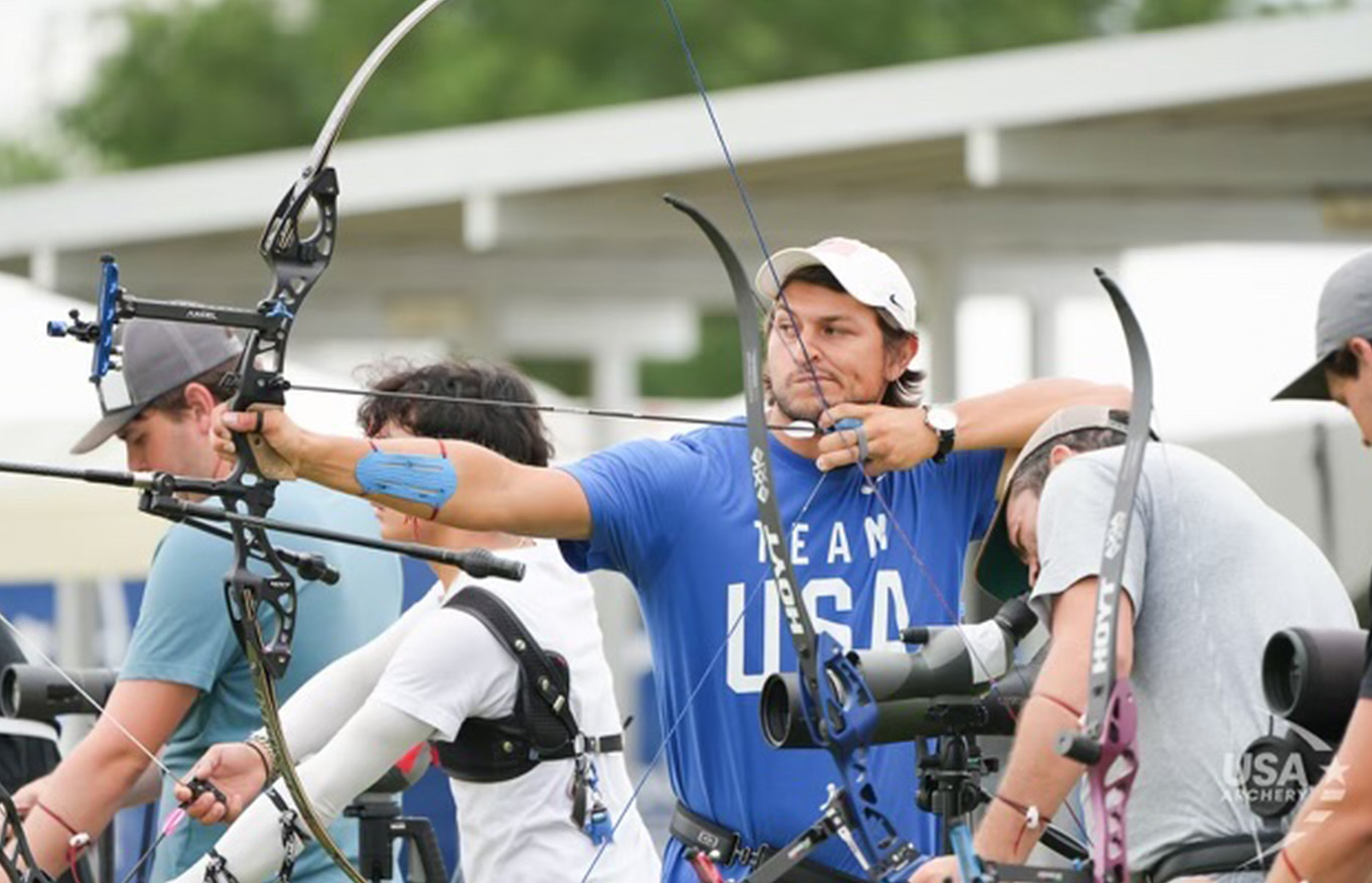 Trenton Cowles is holding up his bow and arrow competing in the USA Archery Olympic Trials.